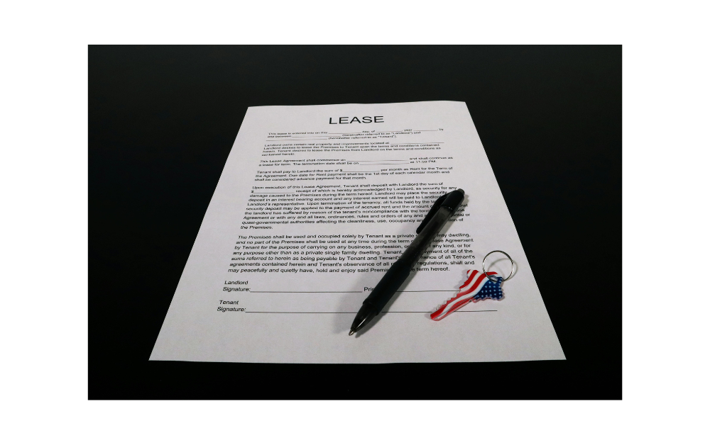 Lease agreement and house keys placed on a wooden table, symbolizing a rental property transaction.